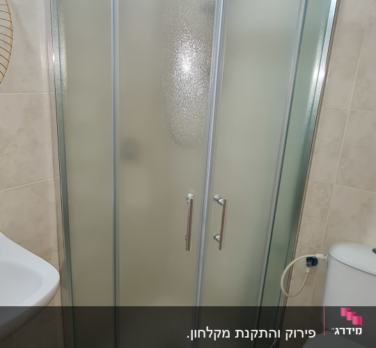 מקלחון זכוכית עם דלתות מתכת בחדר אמבטיה